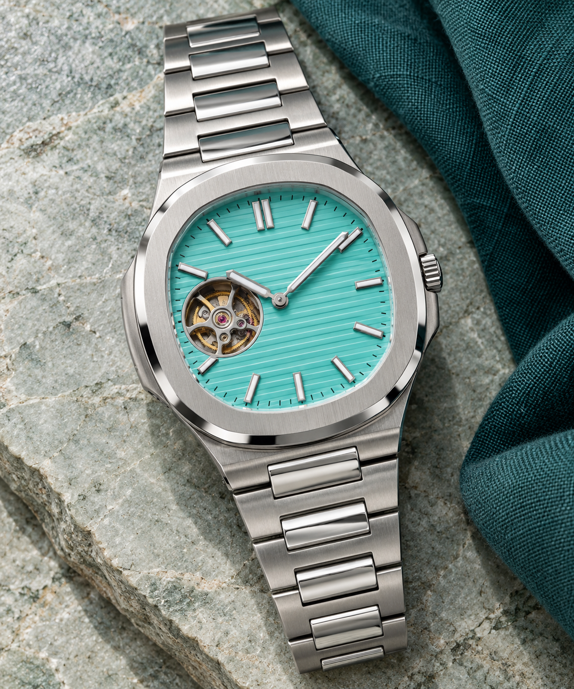 Open Heart Nautiko Aqua integrated-bracelet watch laid diagonally on pale green stone and teal linen