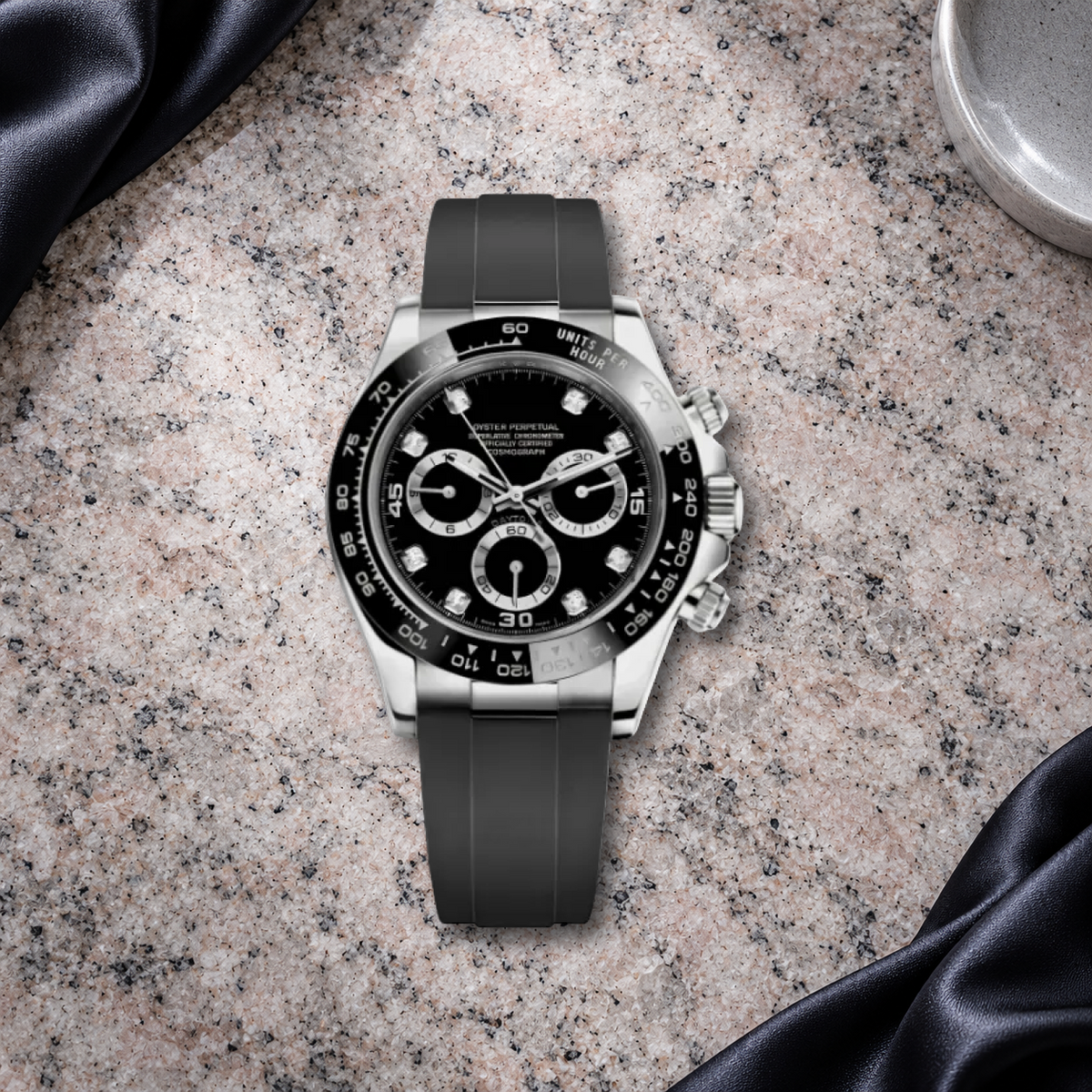 Speedline Gem Black chronograph laid flat on rose-gray granite with dark ink satin