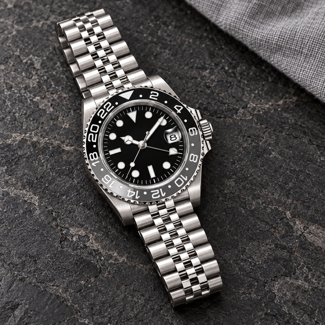 GMT Navigator Grey & Black with Jubilee bracelet laid on charcoal basalt
