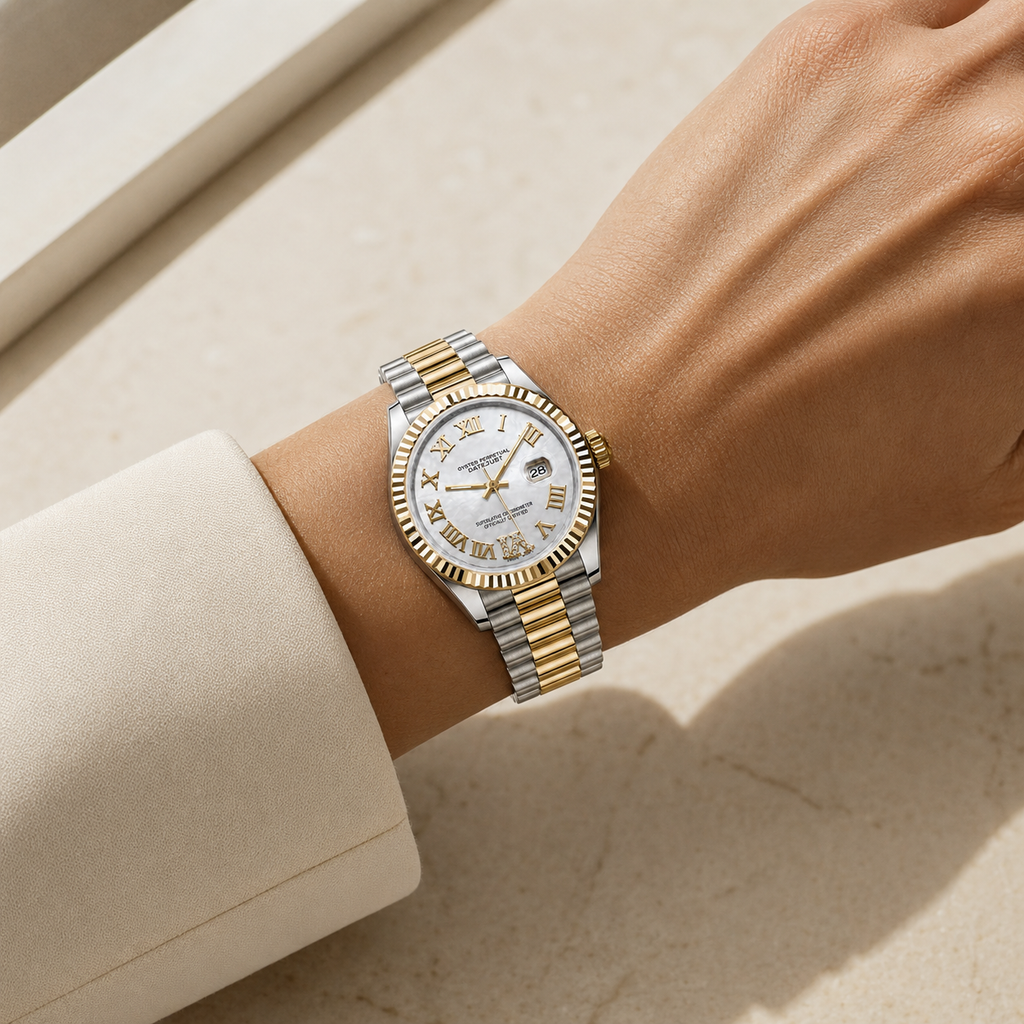 A two-tone stainless steel and gold watch with a white dial and Roman numeral hour markers, shown worn on a person's wrist.