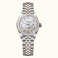  women's Day-Date watch with a two-tone stainless steel and rose gold Oyster bracelet, a white mother-of-pearl dial with Roman numerals, and a bezel set with clear crystals.