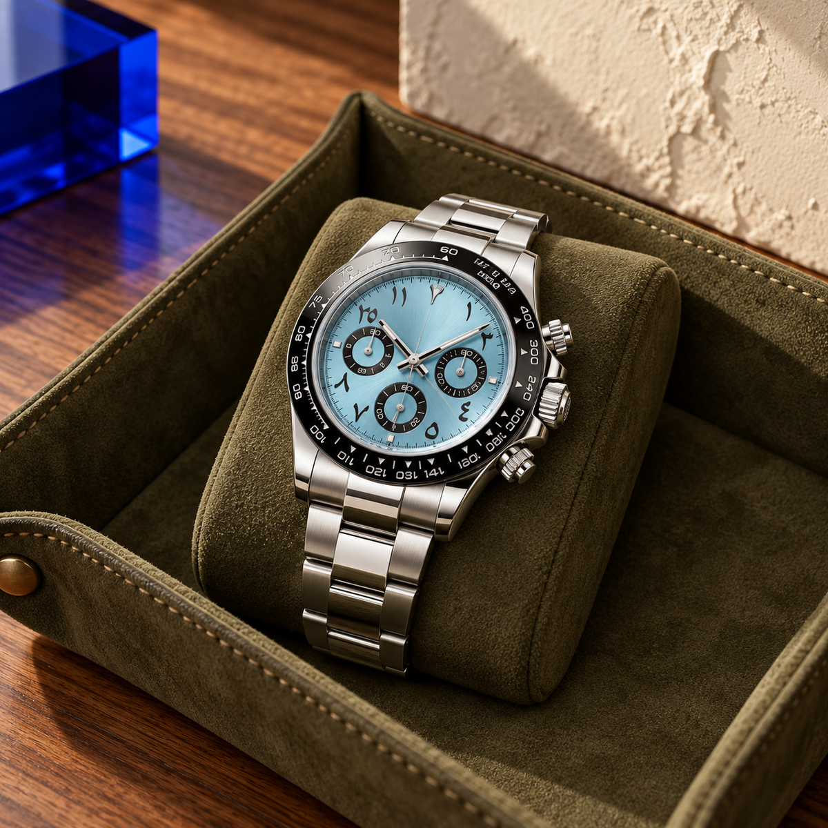Ice blue and black chronograph on a gray watch roll above charcoal wool