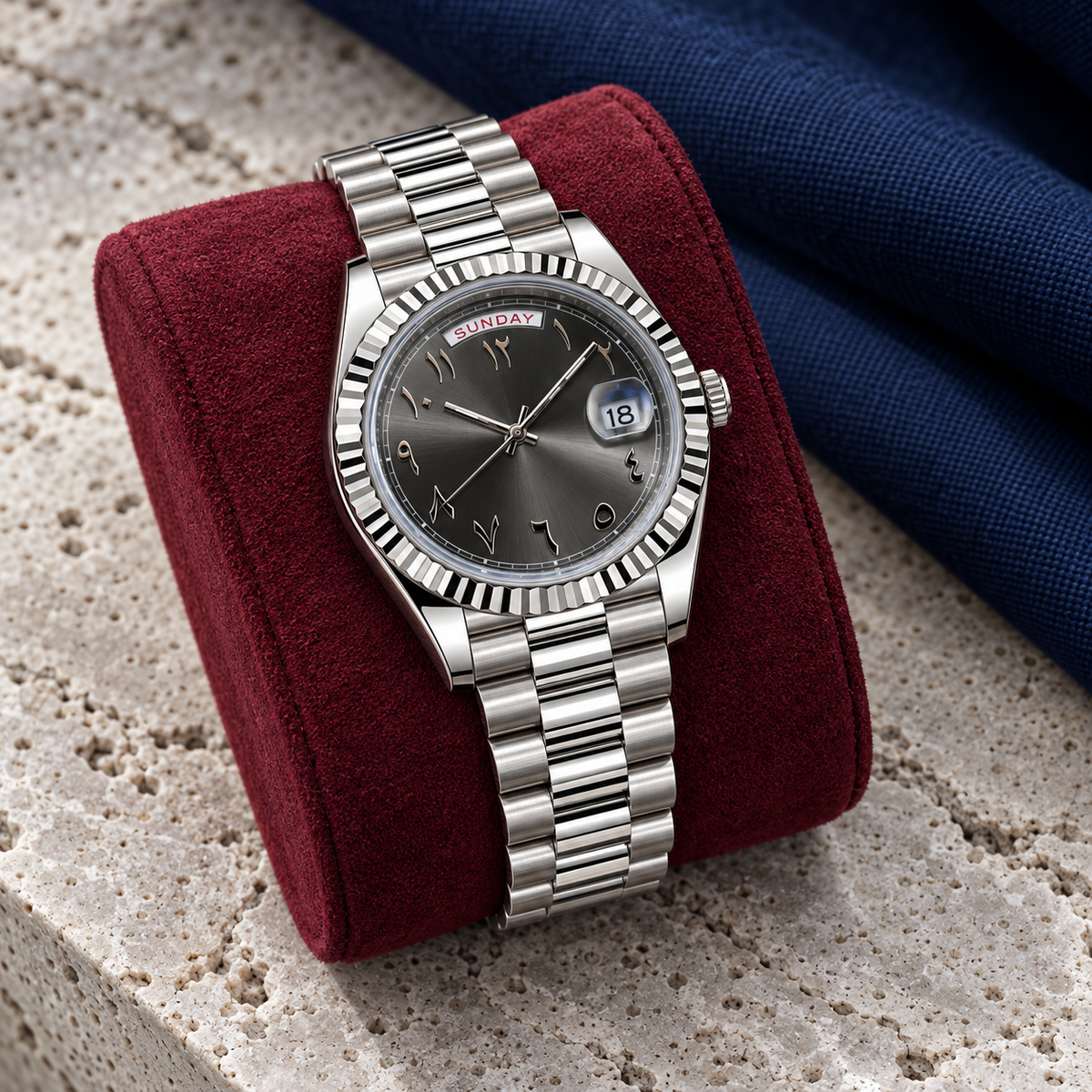 Slate grey day-date Arabic dial watch on wine suede over pale travertine