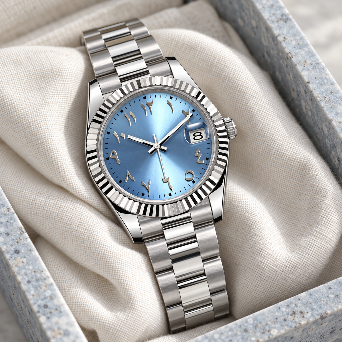Ice-blue Arabic numeral date watch with three-link steel bracelet on ivory linen