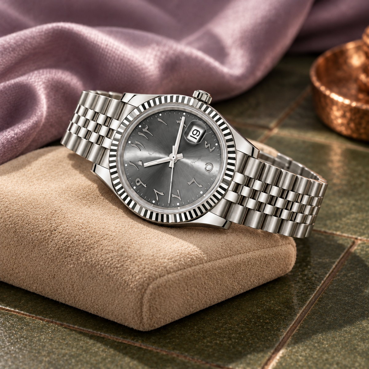 Arabic Heritage slate-grey watch on sand cushion against olive tile