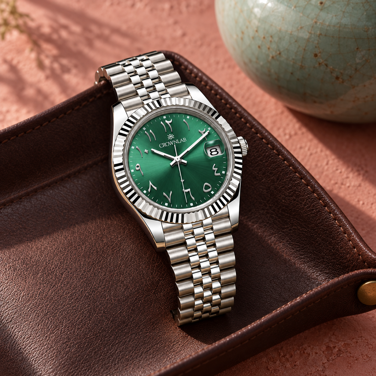 Arabic Heritage emerald green watch on cocoa leather beside rose plaster and celadon ceramic