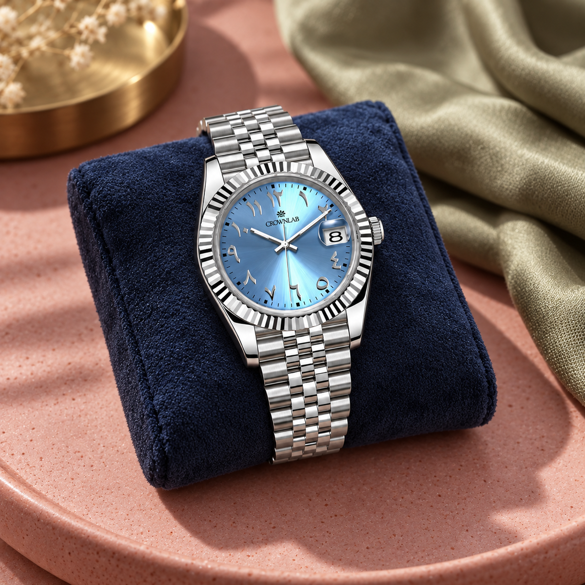 Arabic Heritage glacier-blue watch on navy suede beside rose ceramic