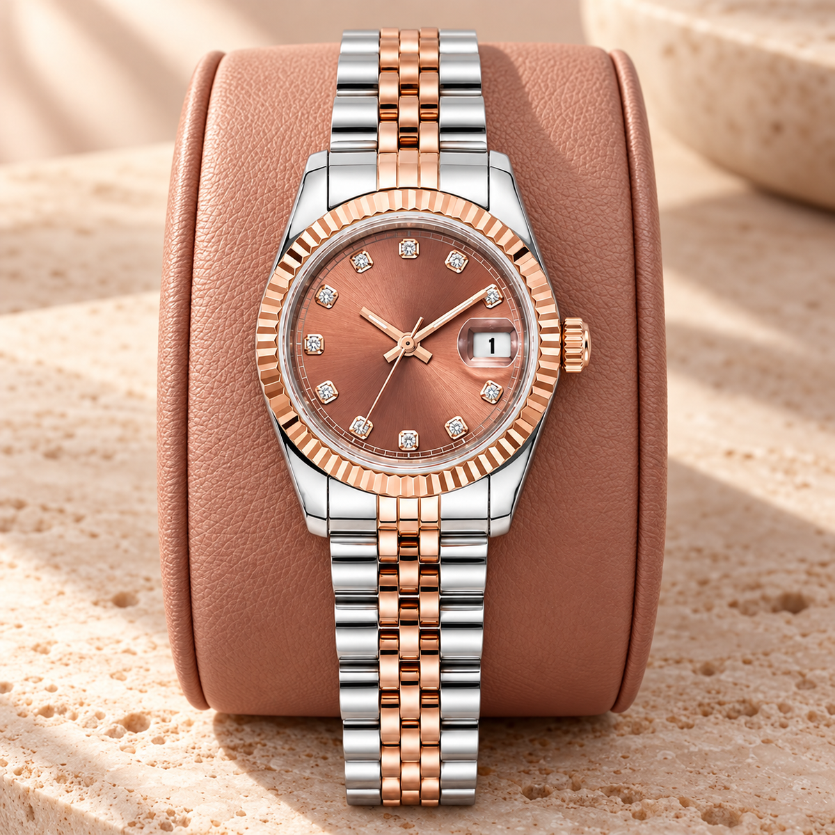 Lady Crownline Rose Blush Two-Tone watch on a rose leather display cushion over travertine; rose sunburst dial and two-tone five-link bracelet.