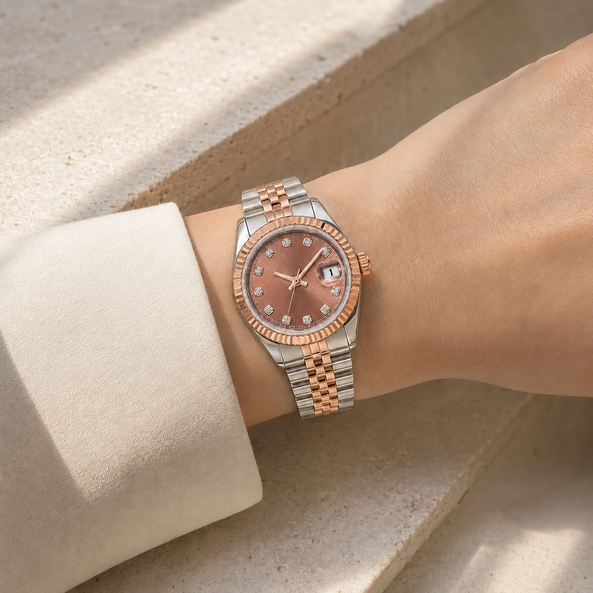 Lady Crownline Rose Blush Two-Tone watch worn with a cream sleeve against pale limestone.