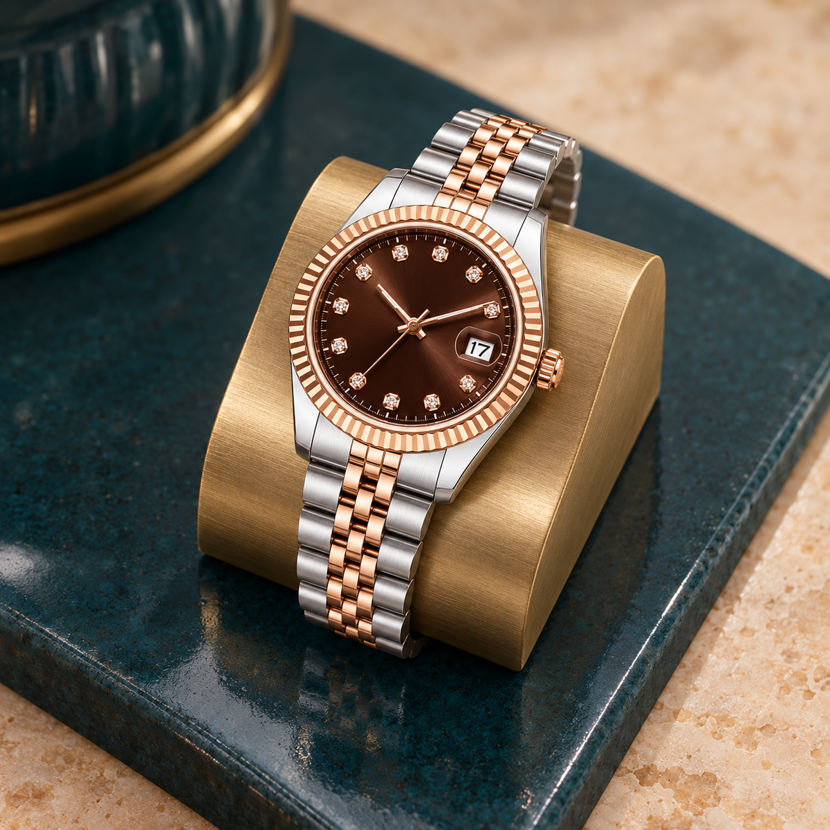 Rose Chocolate Crystal watch showing its crown and two-tone Jubilee bracelet on teal ceramic and brass