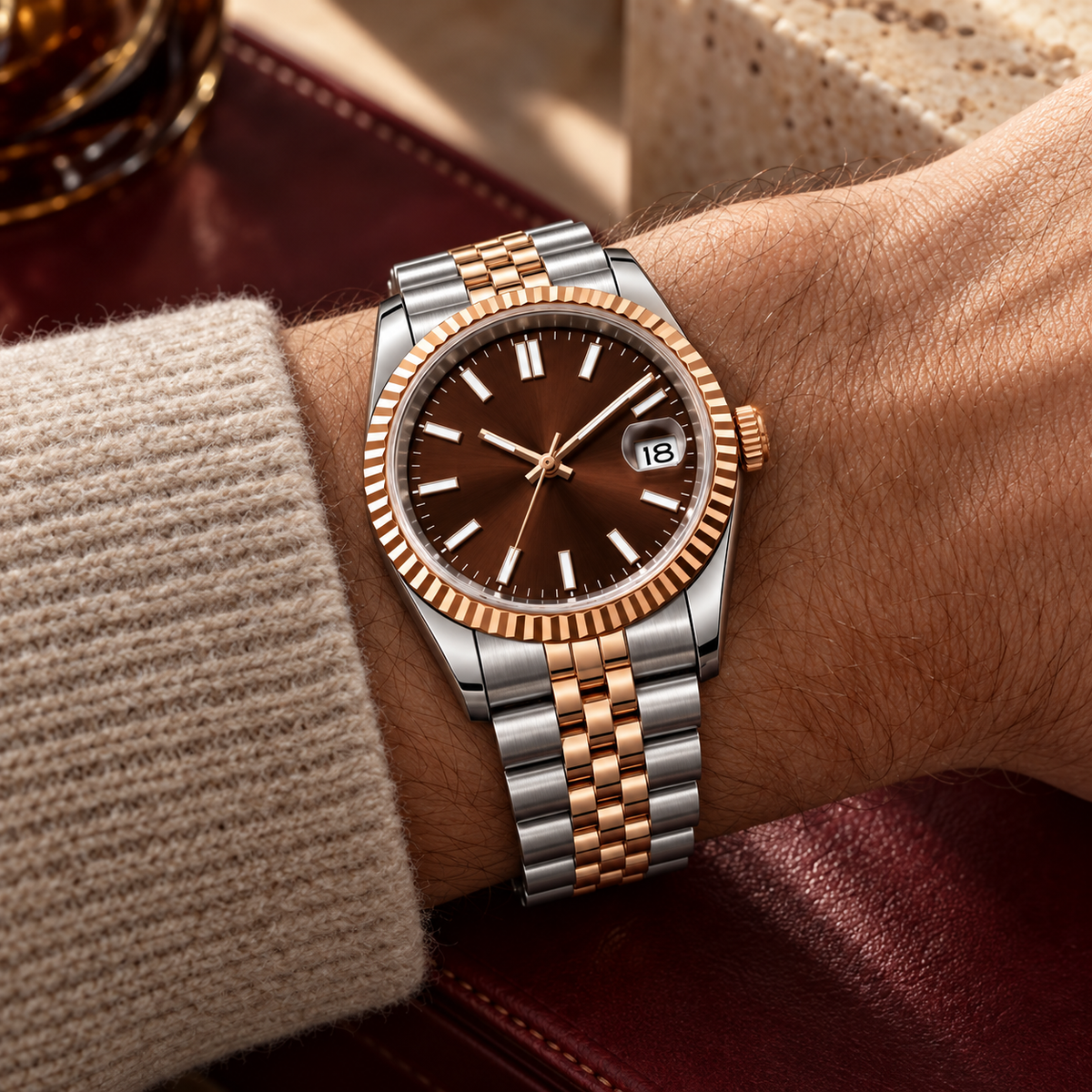Two-tone rose-gold and steel chocolate sunray watch on oatmeal cuff against burgundy leather